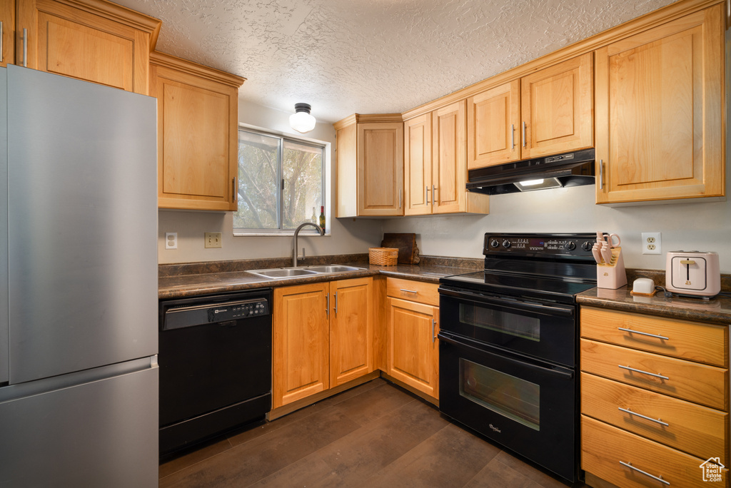 Kitchen featuring a sink, dark countertops, black appliances, and under cabinet range hood