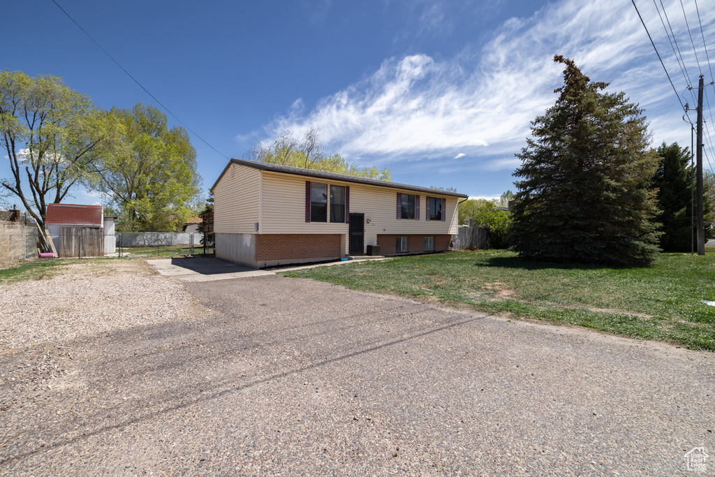 Bi-level home with fence, driveway, and a front lawn