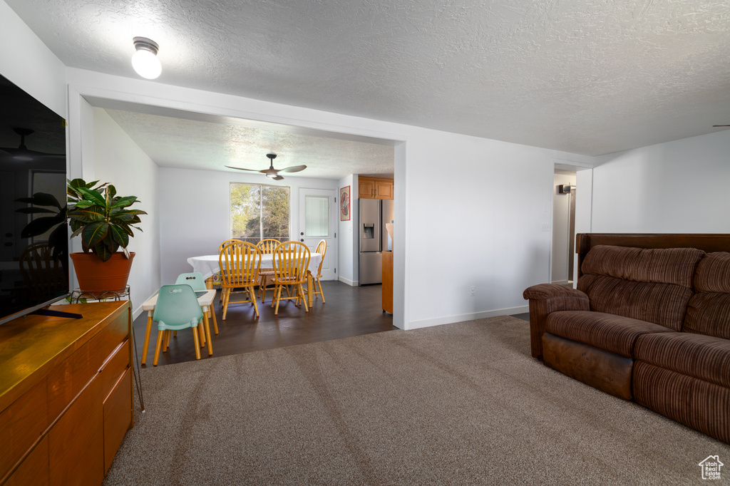 Living room featuring a textured ceiling, baseboards, and dark colored carpet