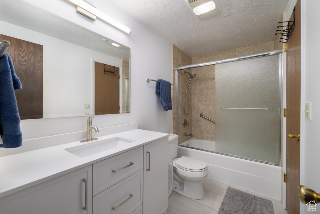 Bathroom featuring vanity, enclosed tub / shower combo, toilet, and a textured ceiling