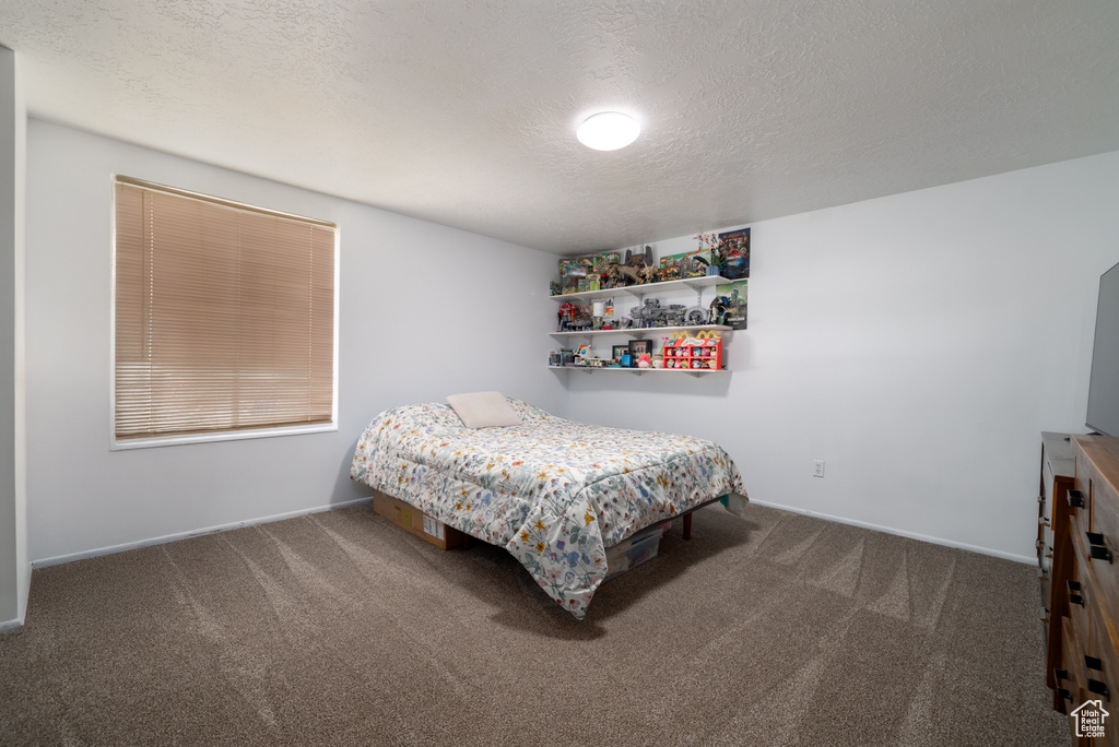 Bedroom with carpet floors, a textured ceiling, and baseboards