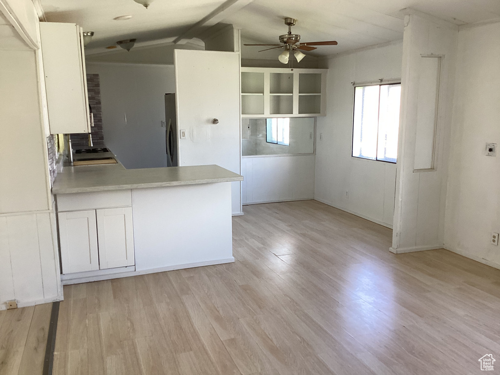 Kitchen featuring stainless steel fridge, ceiling fan, a peninsula, and white cabinetry