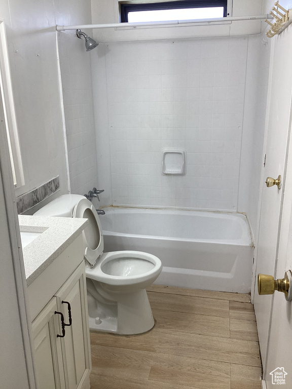 Bathroom with shower / tub combination, toilet, wood finished floors, and vanity