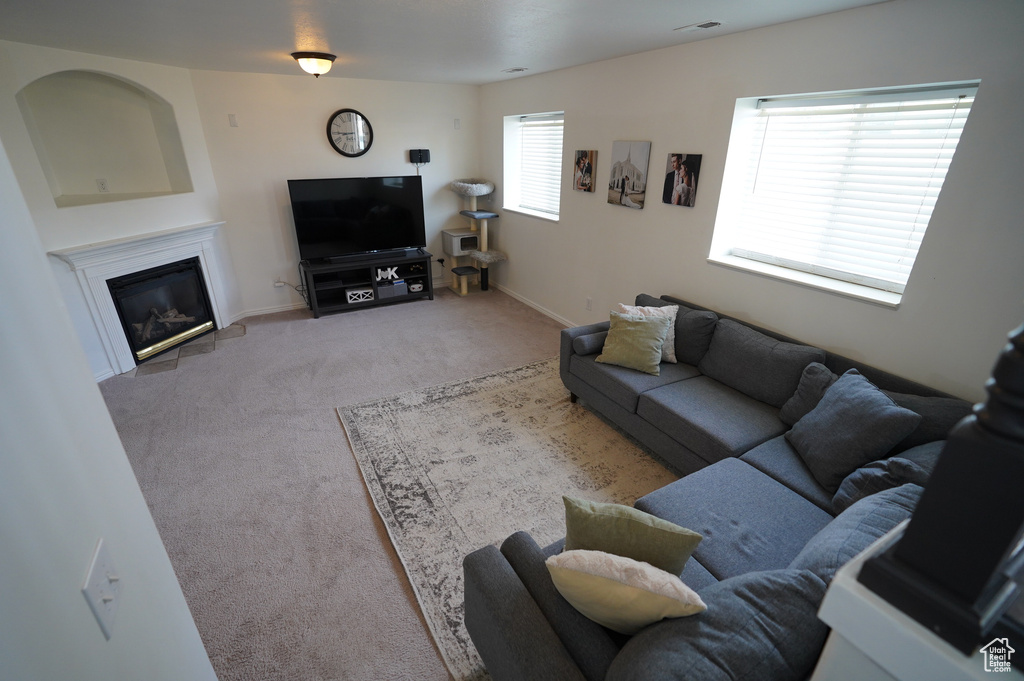 Living area with light colored carpet, a glass covered fireplace, and baseboards