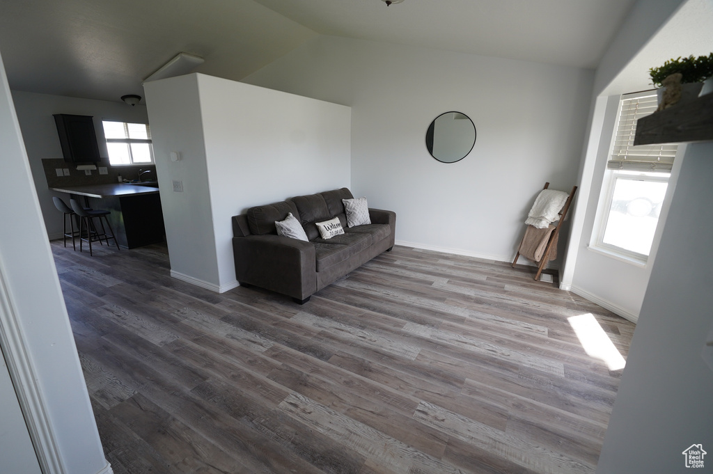 Living area featuring baseboards, wood finished floors, and vaulted ceiling