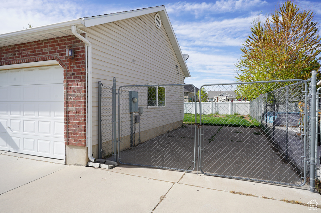 View of property exterior with fence, a gate, brick siding, and a garage