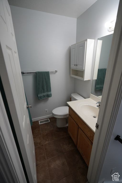 Bathroom featuring visible vents, toilet, vanity, and baseboards
