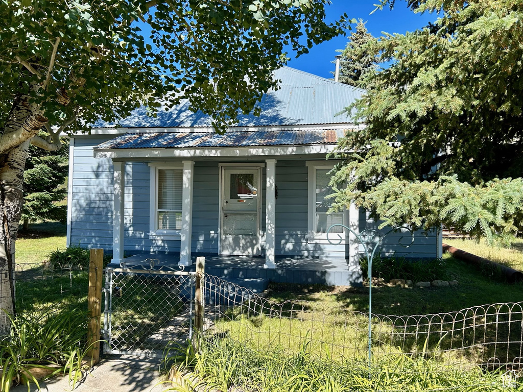 View of front of property featuring a gate, covered porch, a fenced front yard, and metal roof
