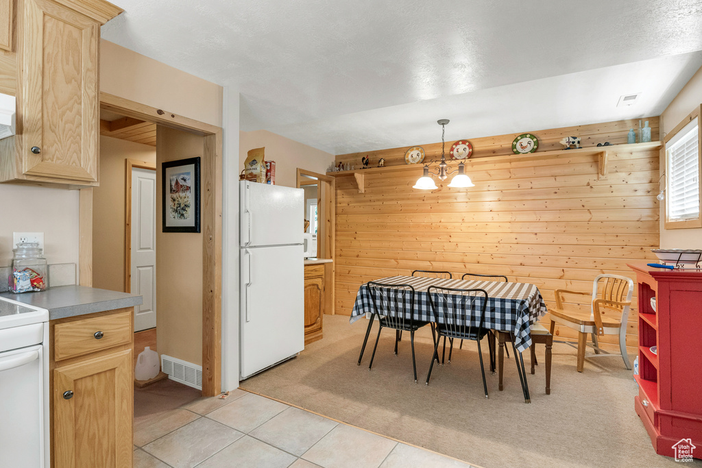 Dining space featuring wooden walls, a notable chandelier, light tile patterned flooring, and visible vents