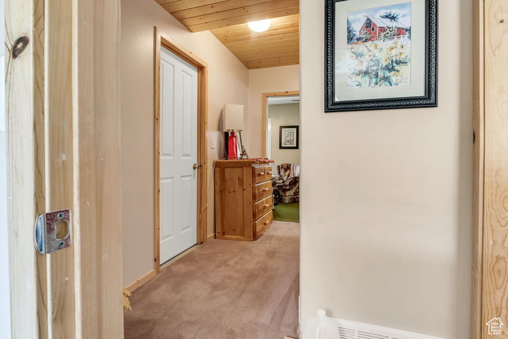 Hallway with visible vents, baseboards, light colored carpet, and wood ceiling