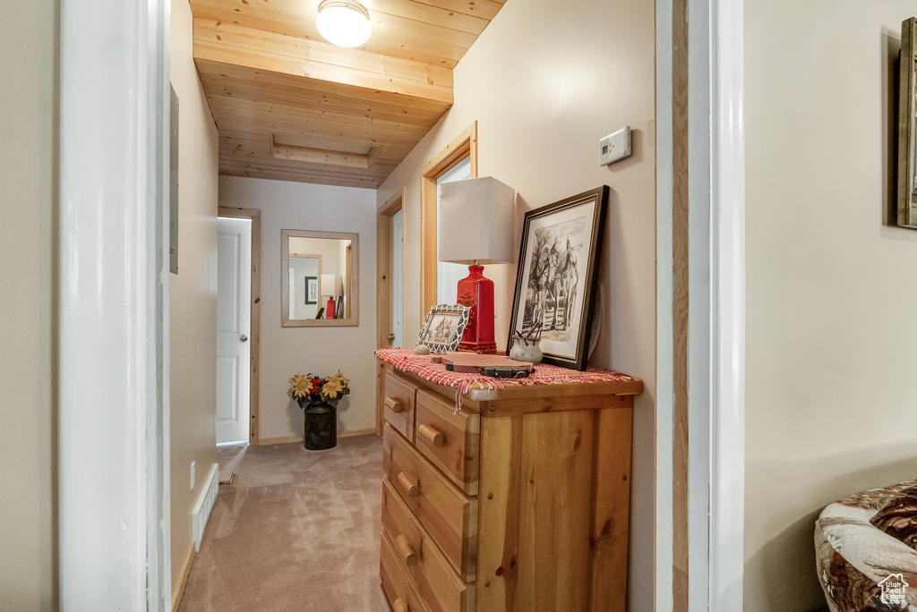 Corridor with wood ceiling, light colored carpet, and baseboards