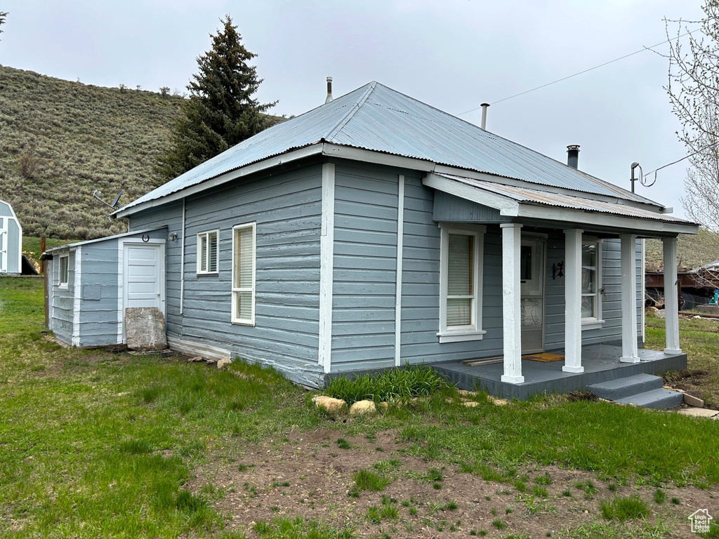 View of side of property with a porch and metal roof