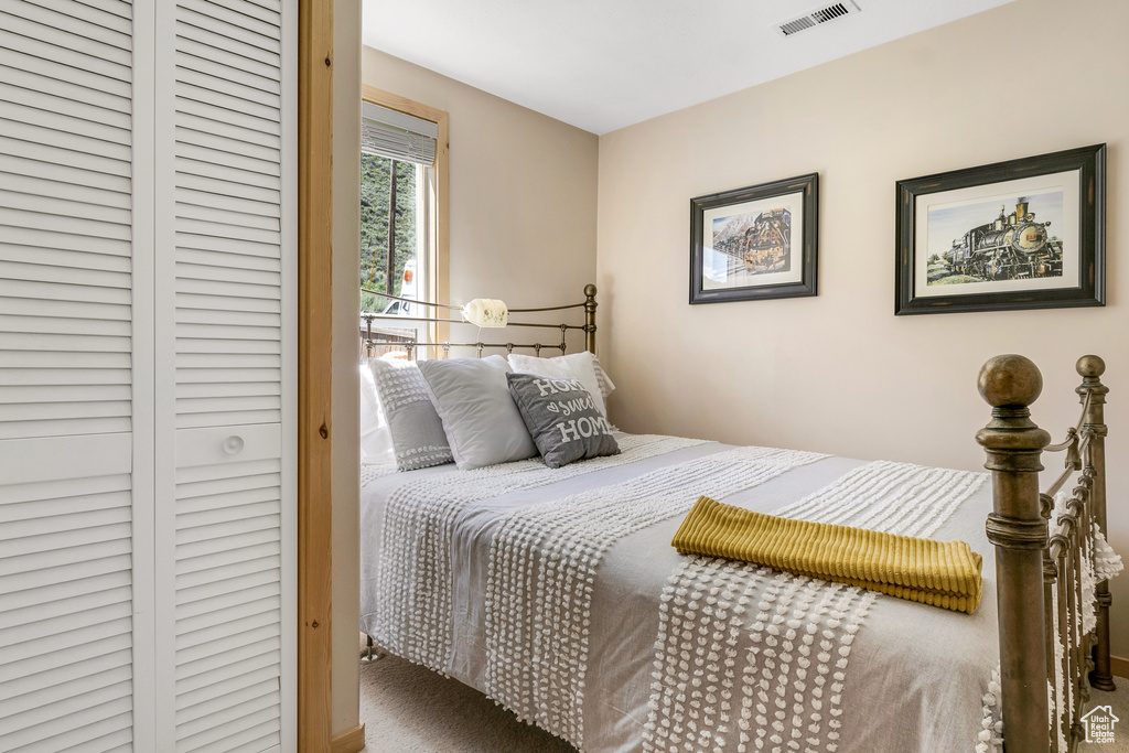 Bedroom with visible vents, carpet floors, and a closet