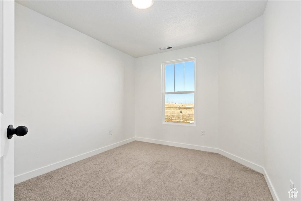 Carpeted empty room with visible vents and baseboards