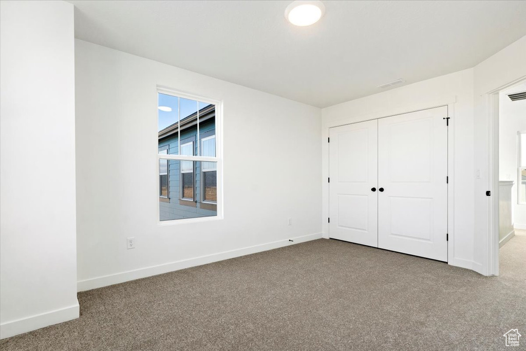 Unfurnished bedroom featuring baseboards, carpet flooring, and a closet