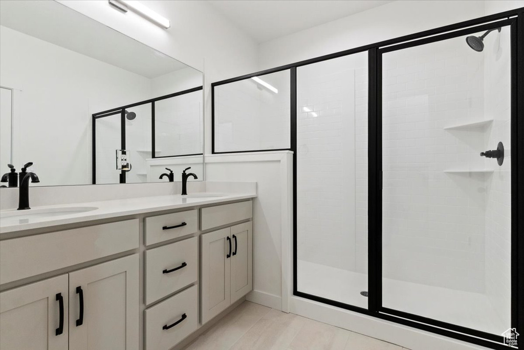 Bathroom with a sink, a shower stall, and double vanity