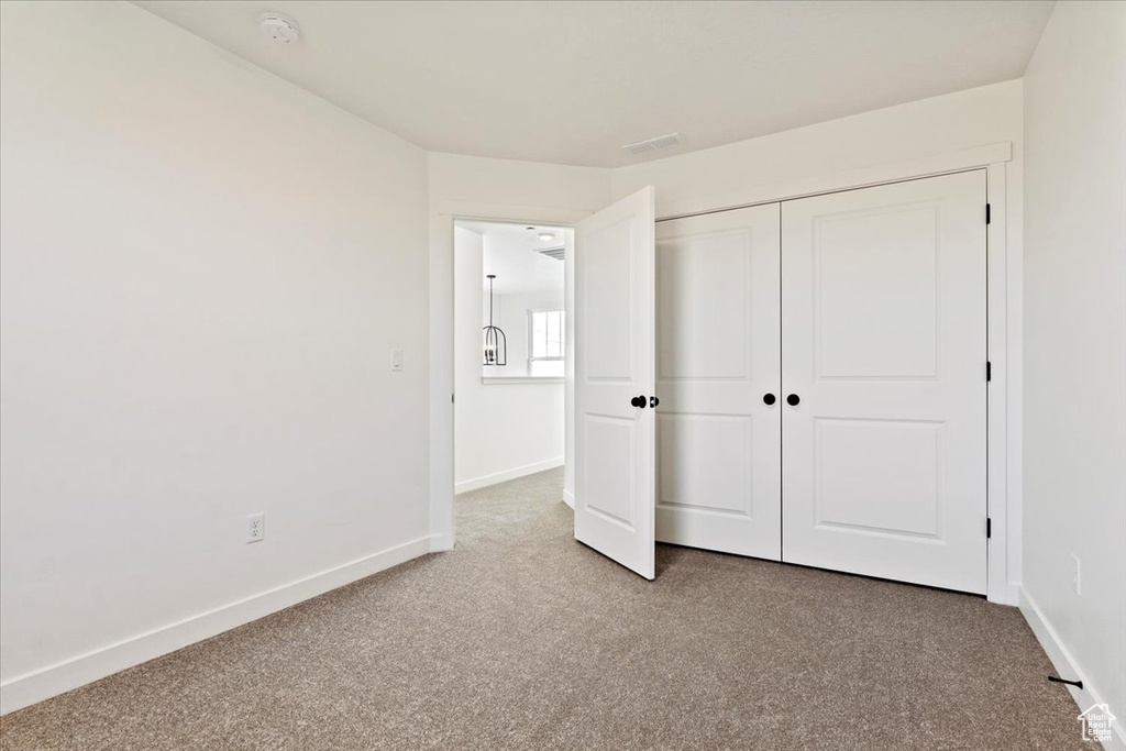 Unfurnished bedroom featuring carpet, a closet, and baseboards