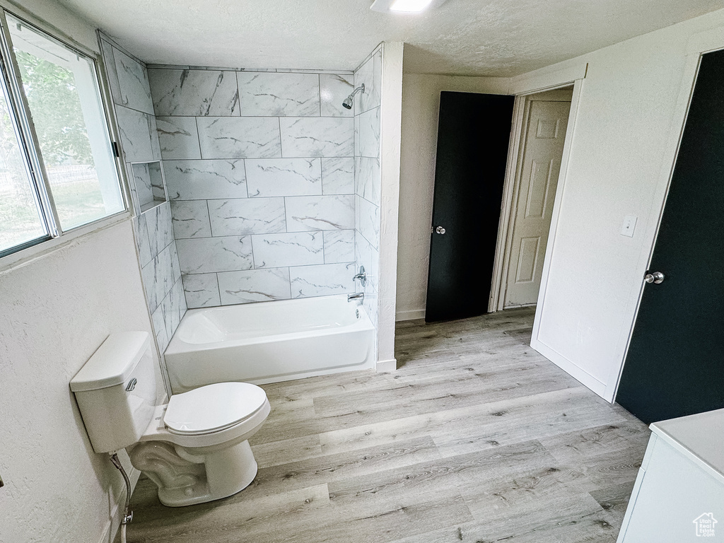 Full bathroom featuring shower / tub combination, a textured ceiling, wood finished floors, and toilet
