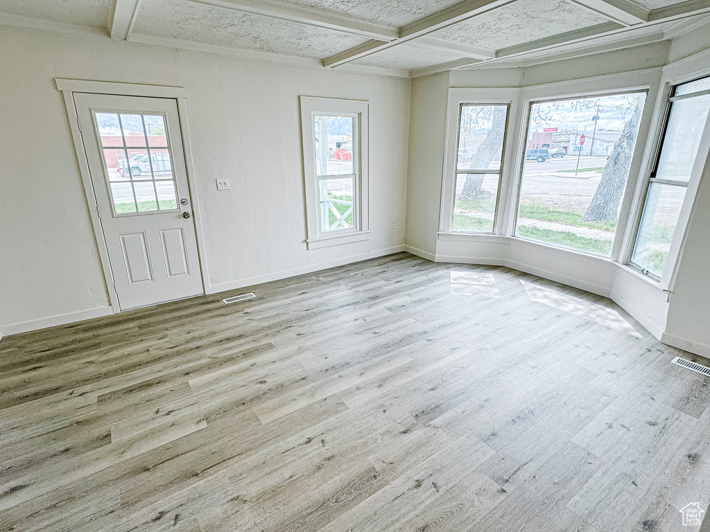 Unfurnished room featuring visible vents, wood finished floors, and coffered ceiling
