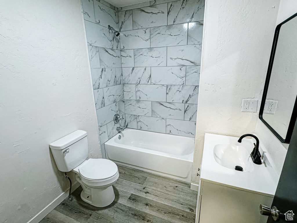 Full bath with toilet, wood finished floors, vanity, and a textured wall