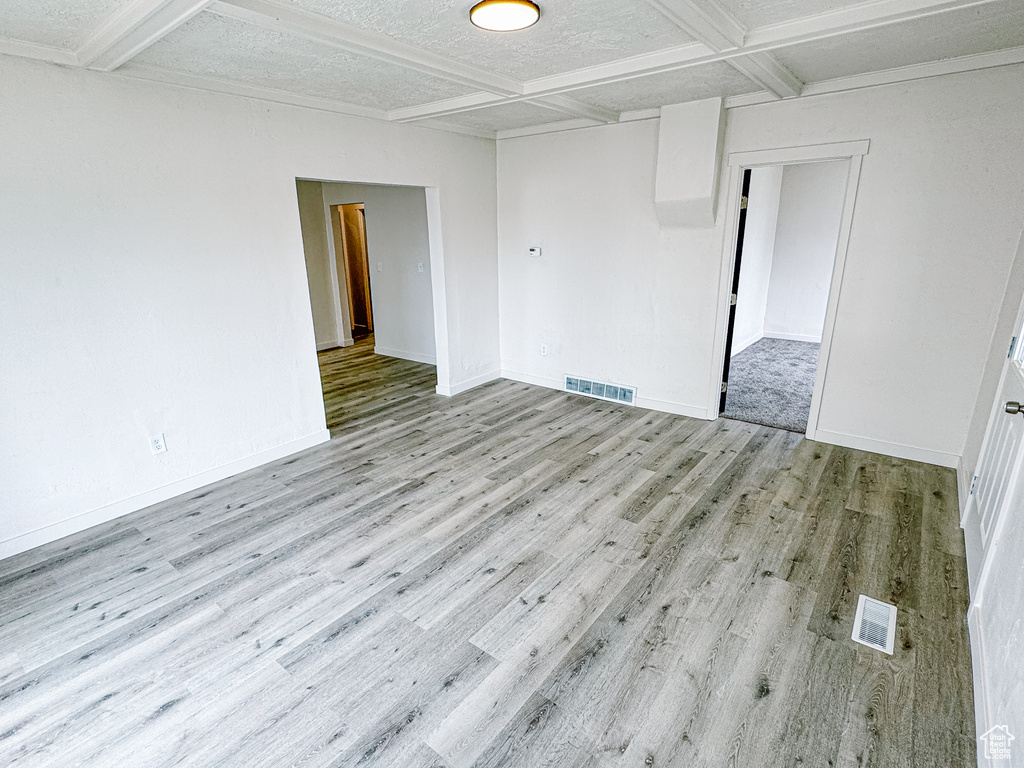 Unfurnished room with baseboards, visible vents, wood finished floors, and coffered ceiling