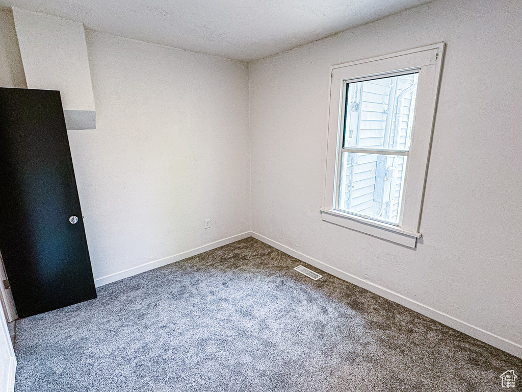 Carpeted spare room with visible vents and baseboards
