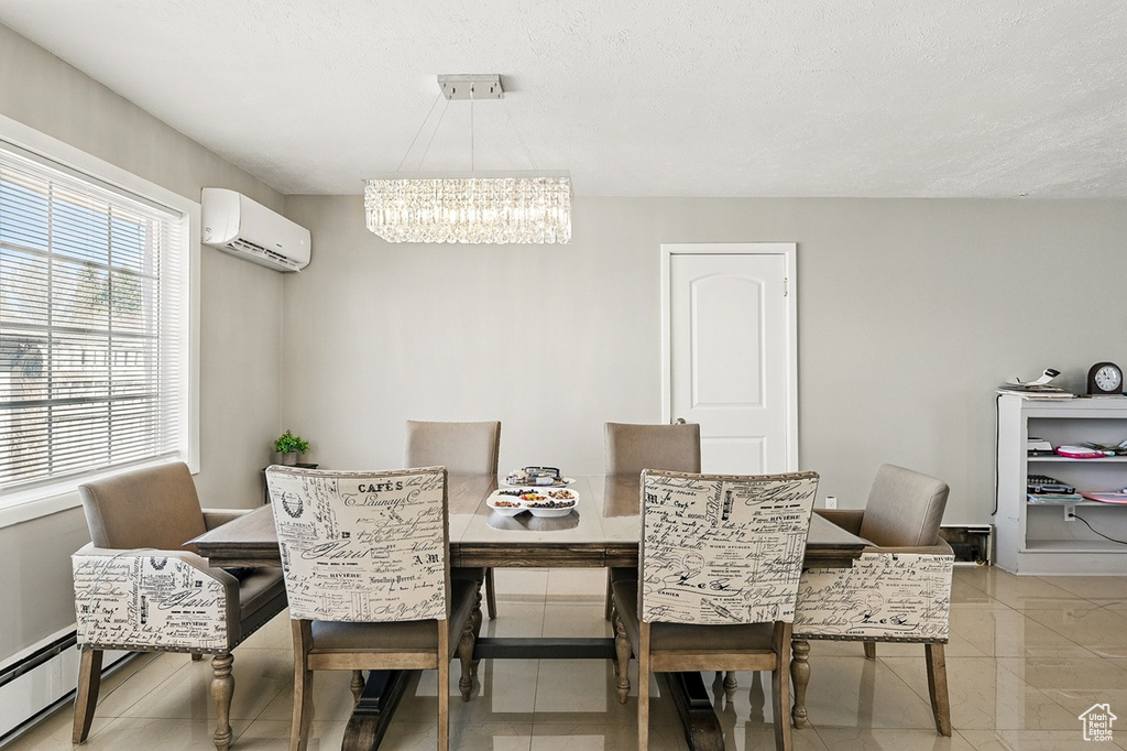 Dining area with baseboard heating, an AC wall unit, a chandelier, and light tile patterned floors