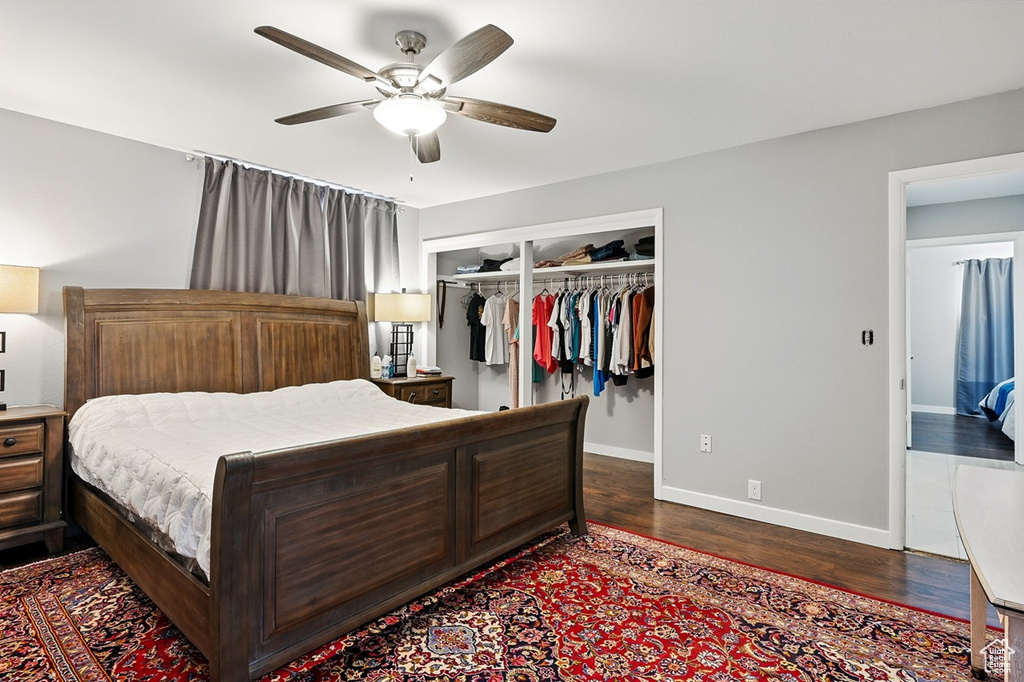Bedroom with dark wood finished floors, baseboards, ceiling fan, and a closet
