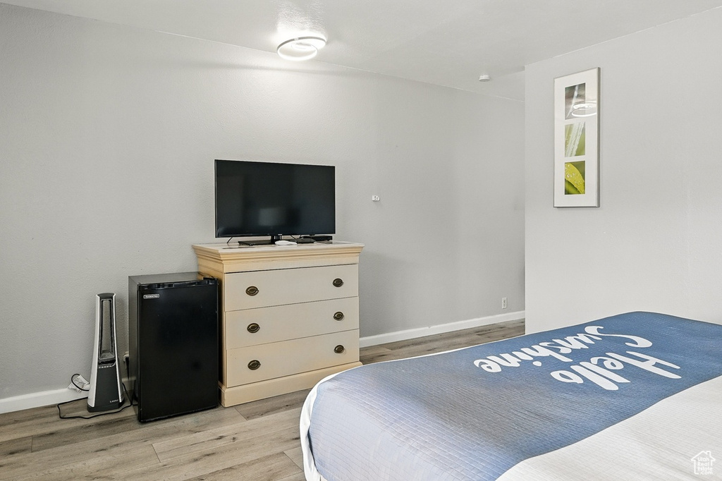 Bedroom featuring baseboards, freestanding refrigerator, and light wood-style flooring