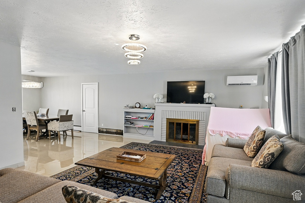 Living room with a textured ceiling, a brick fireplace, a wall mounted AC, and a chandelier