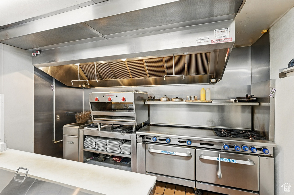 Kitchen with wall chimney exhaust hood, tile patterned flooring, and double oven range