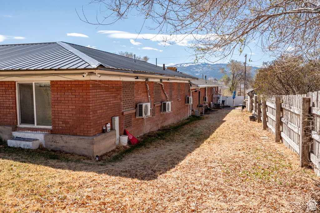 View of home\\\'s exterior featuring brick siding, fence, ac unit, and metal roof