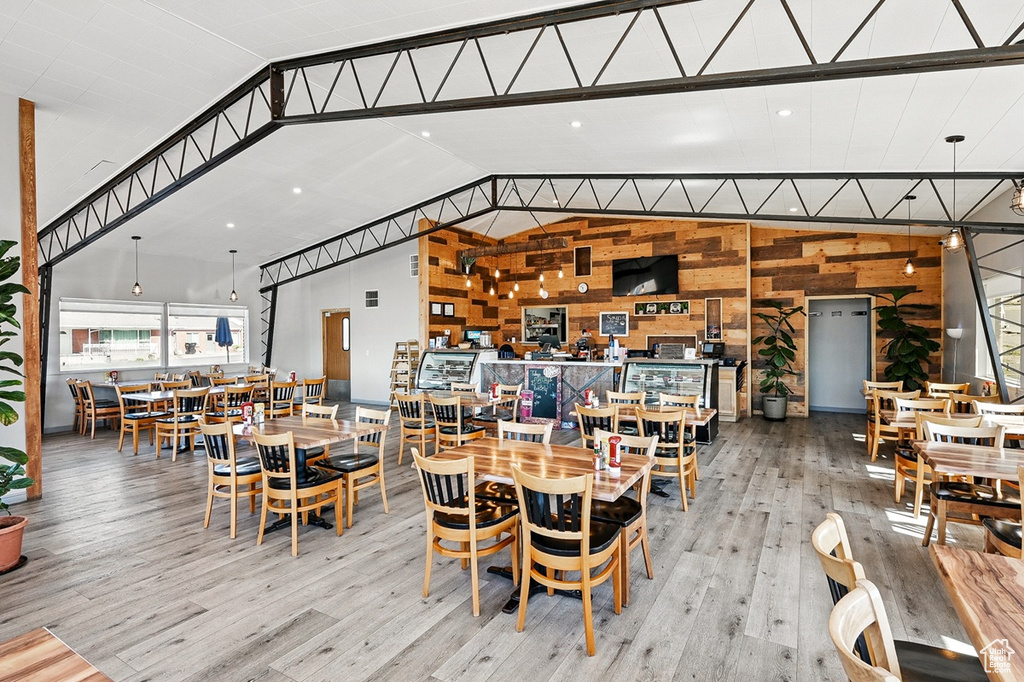 Dining room with vaulted ceiling, wood walls, and wood finished floors