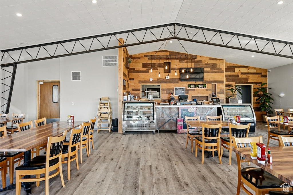 Dining area featuring wooden walls, vaulted ceiling, wood finished floors, and visible vents
