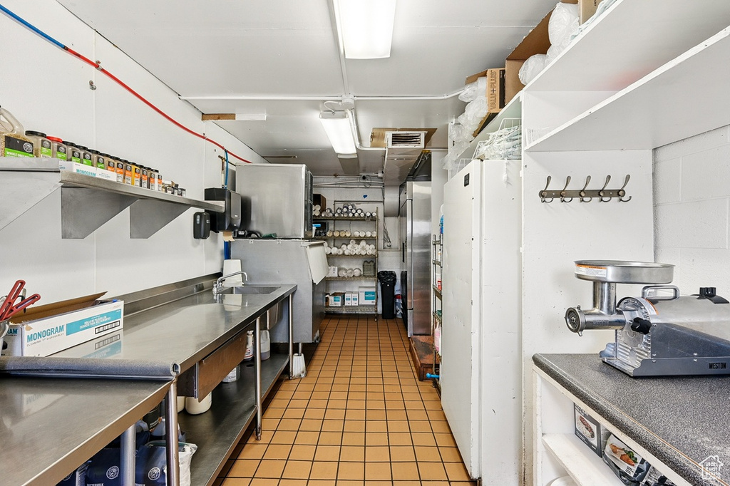 Kitchen featuring open shelves, visible vents, a sink, light tile patterned floors, and stainless steel counters