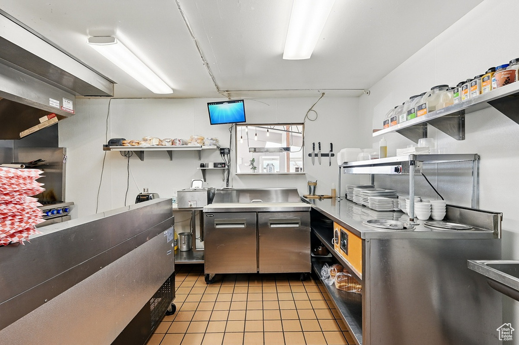 Kitchen featuring open shelves, stainless steel countertops, and light tile patterned floors