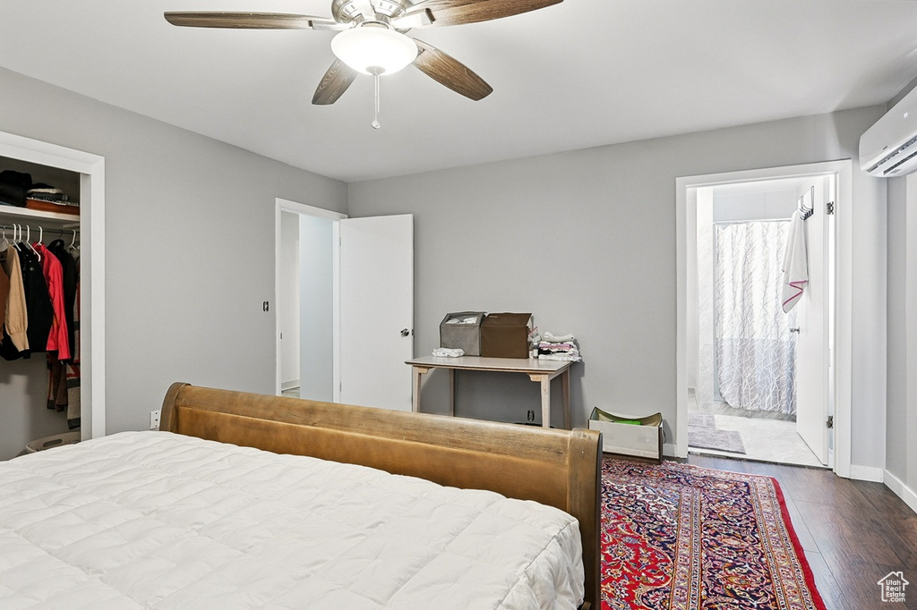 Bedroom with a ceiling fan, a closet, a wall mounted AC, baseboards, and dark wood-type flooring