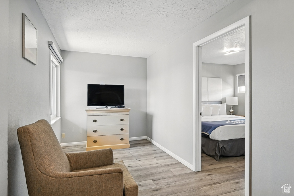 Sitting room featuring a textured ceiling, light wood finished floors, and baseboards