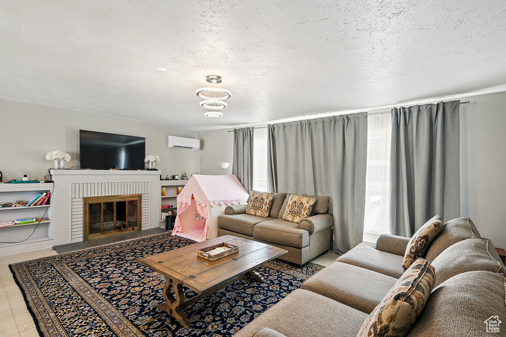 Living area with a brick fireplace, a wall mounted AC, and a textured ceiling