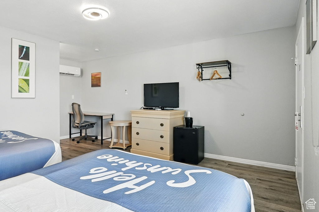 Bedroom featuring baseboards, wood finished floors, and a wall mounted air conditioner