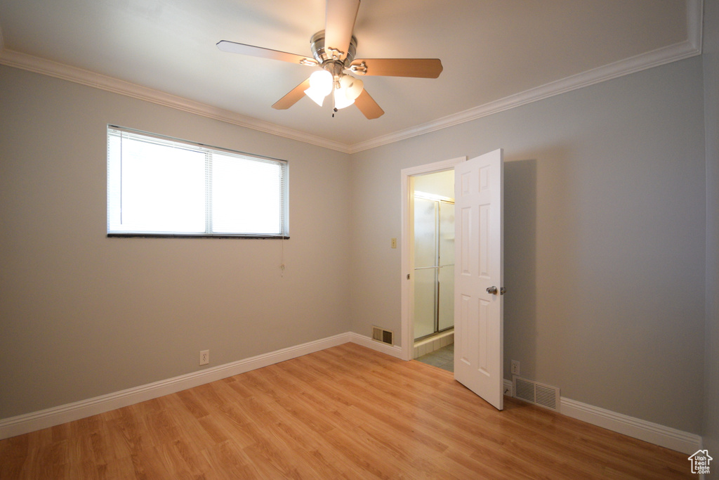 Empty room with visible vents, ceiling fan, light wood-type flooring, and ornamental molding