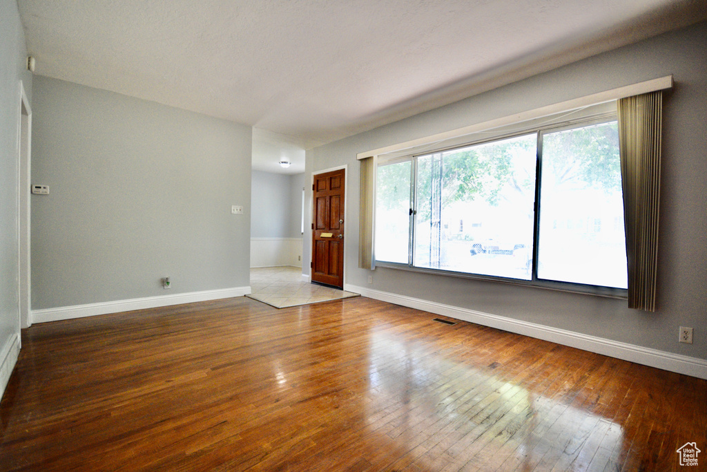Empty room featuring visible vents, hardwood / wood-style floors, and baseboards