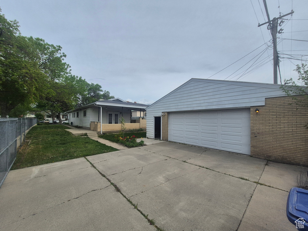 View of front facade featuring an outbuilding, fence, brick siding, a front lawn, and a garage