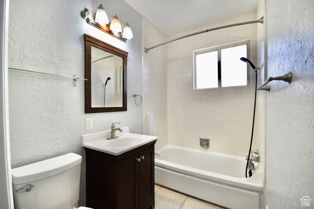 Bathroom with tile patterned floors, toilet, shower / bath combination, a textured wall, and vanity