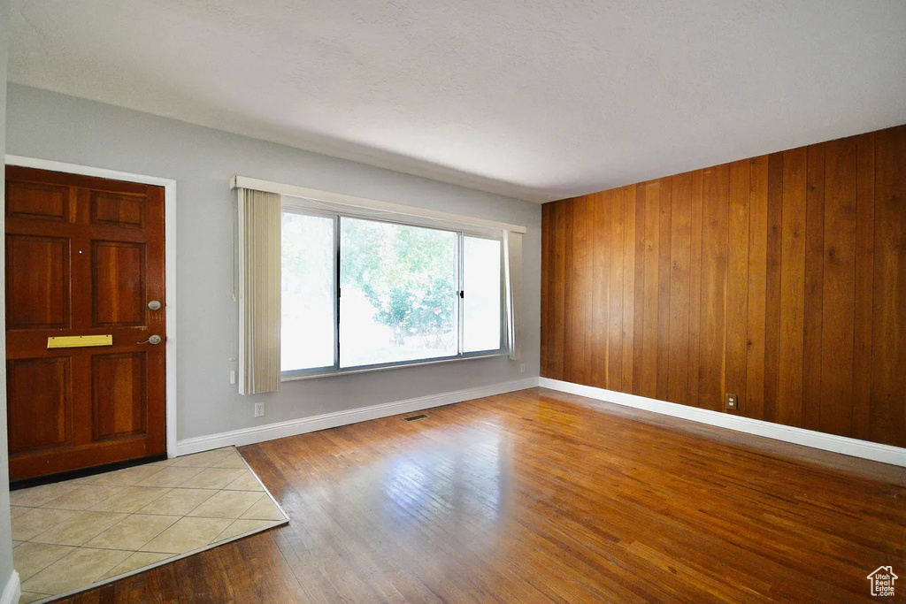 Entrance foyer with baseboards, visible vents, wood finished floors, and wooden walls