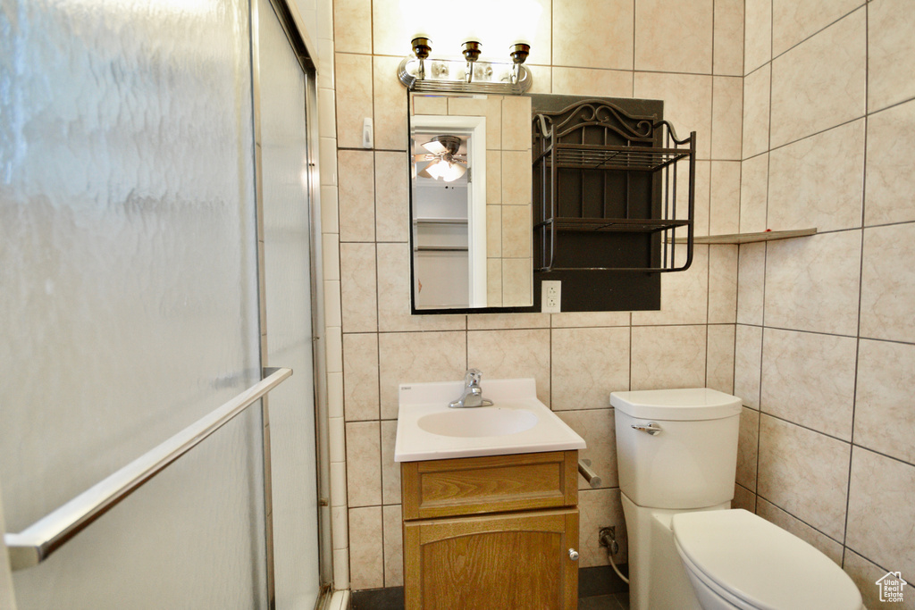 Full bathroom featuring toilet, tile walls, a shower stall, and vanity
