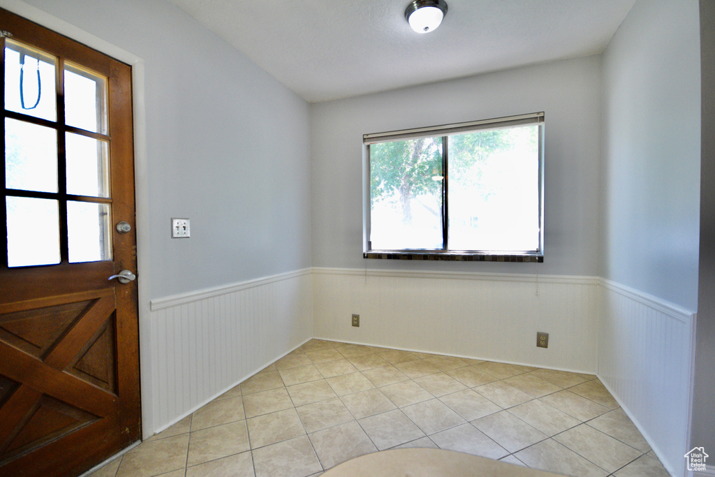 Spare room with light tile patterned flooring and wainscoting