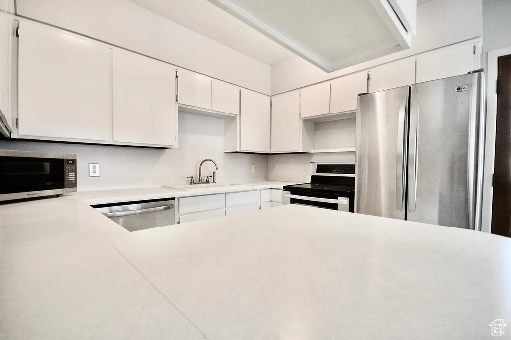 Kitchen featuring white cabinetry, a sink, appliances with stainless steel finishes, and light countertops