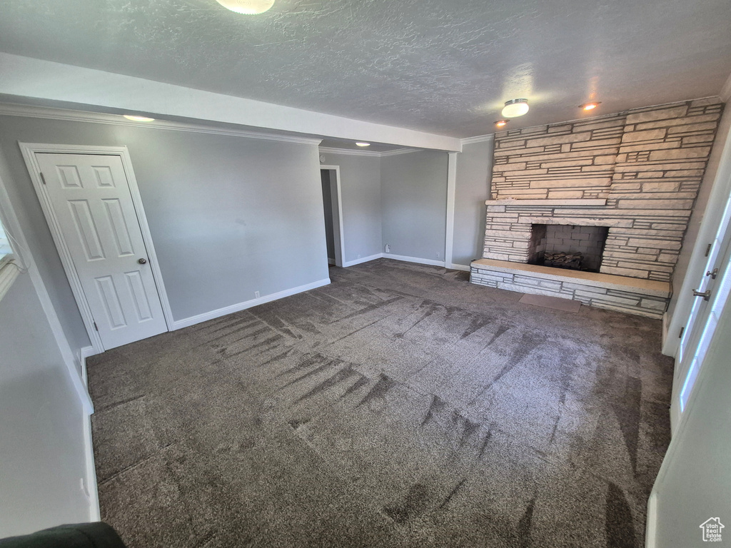 Unfurnished living room featuring ornamental molding, baseboards, carpet, and a fireplace
