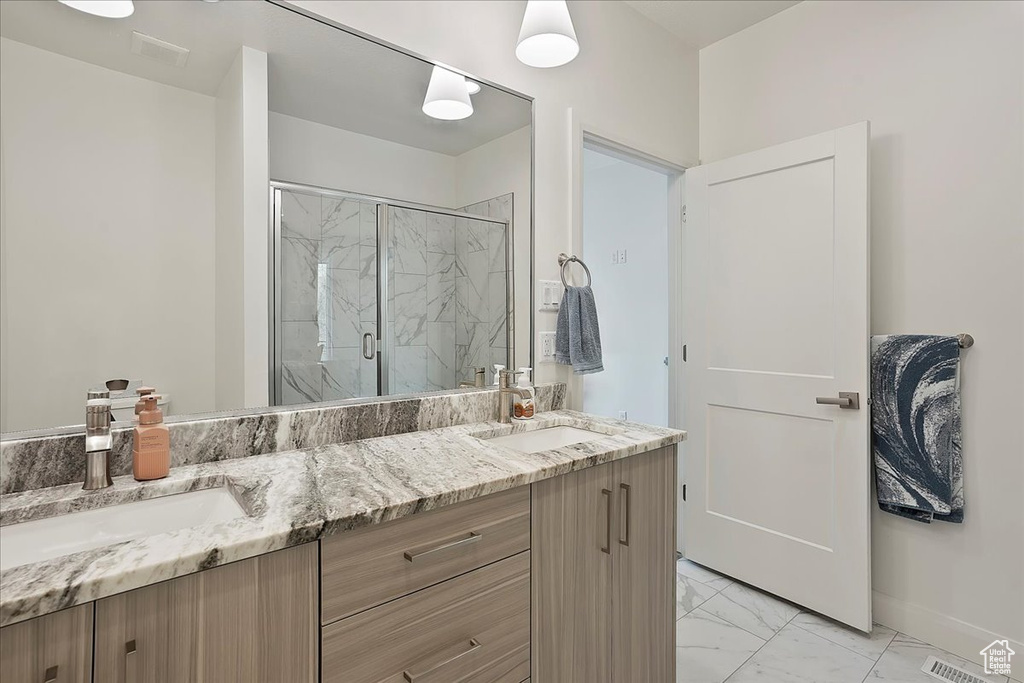 Full bath featuring a marble finish shower, marble finish floor, double vanity, and a sink